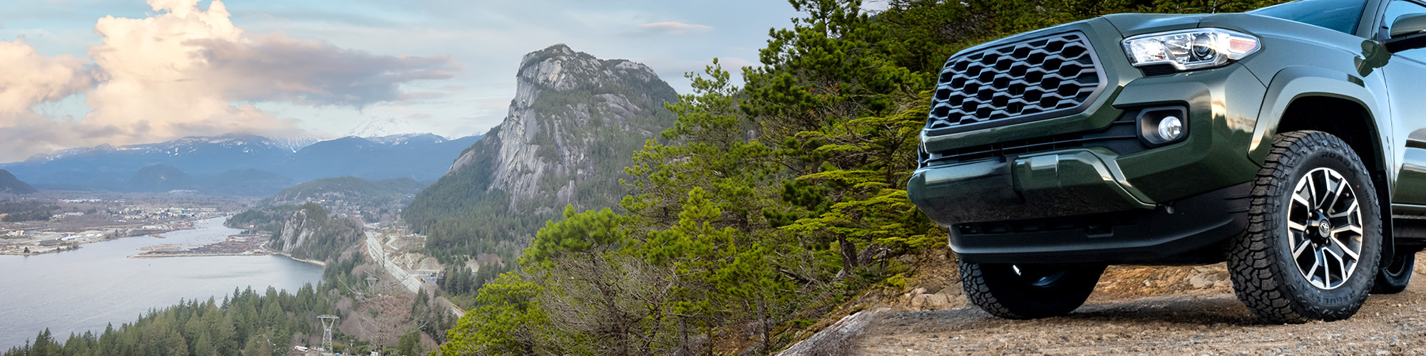 Pickup truck equipped with RoadX all-terrain tires overlooking a scenic mountain and coastal landscape in Canada.